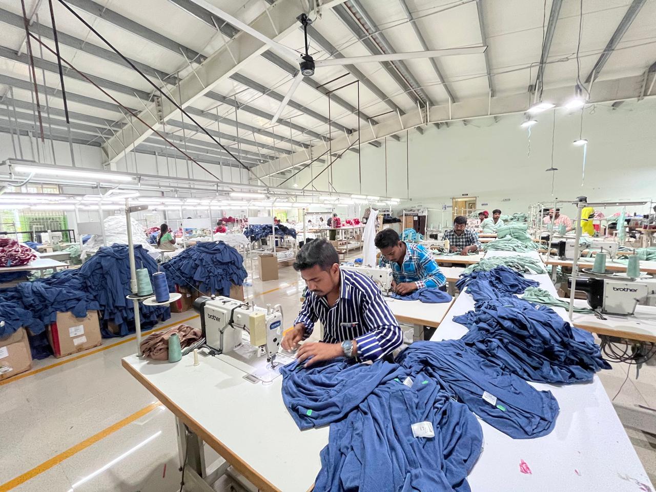 Modern clothing manufacturing facility with workers operating machinery